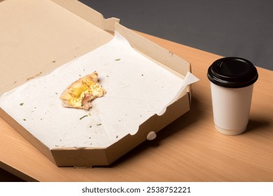 An empty pizza box with a single slice of pizza and a takeaway coffee cup on a wooden table. Perfect for illustrating office lunch breaks or casual dining scenes. - Powered by Shutterstock