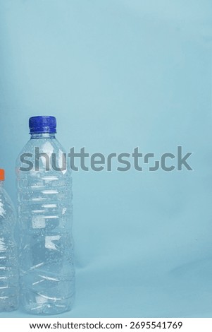 Empty plastic bottle with blue cap standing on a blue background, representing recycling, plastic waste, and environmental awareness.