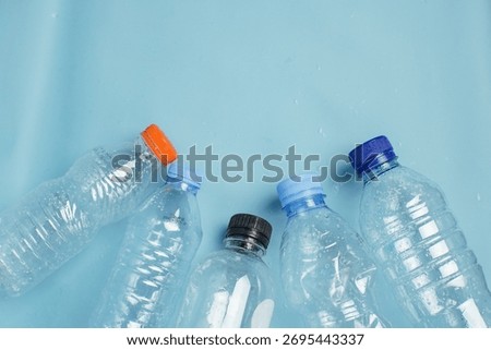 Empty plastic bottles arranged on blue background, symbolizing recycling, plastic waste management, and environmental awareness.