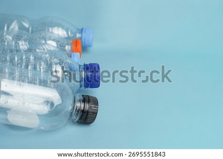 Empty plastic bottles arranged in a row on a blue surface, symbolizing recycling, plastic waste management, and environmental protection.