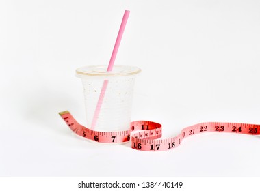 Empty Plastic Cup Of Milk Ice Tea With Measuring Tape On White Background. Selective Focus.