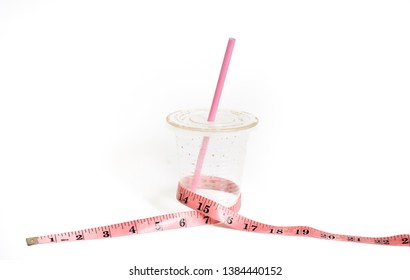 Empty Plastic Cup Of Milk Ice Tea With Measuring Tape On White Background. Selective Focus.