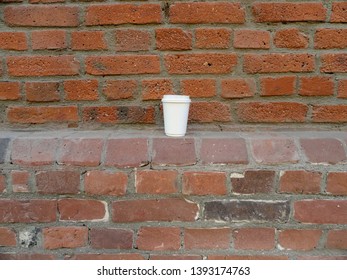 Empty plastic cup on the old brick wall. Moscow, Russia.