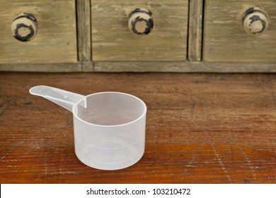 empty plastic measuring cup on a grunge wooden counter with drawer cabinet