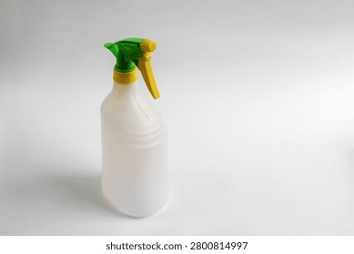 Empty plastic trigger spray bottle isolated on white background, reusable household cleaning container with green and yellow nozzle, studio product photo with copy space.