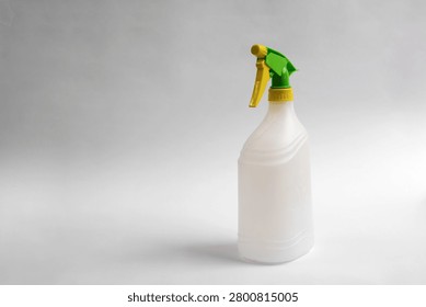 Empty plastic trigger spray bottle isolated on white background, reusable household cleaning container with green and yellow nozzle, studio product photo with copy space.