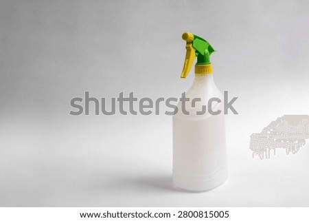 Empty plastic trigger spray bottle isolated on white background, reusable household cleaning container with green and yellow nozzle, studio product photo with copy space.
