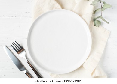 An Empty Plate And Cutlery On A White Table.