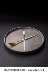Empty plate with devices in the form of clock hands as a conceptual background for lunch time, coffee break, meal