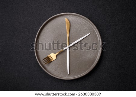 Empty plate with devices in the form of clock hands as a conceptual background for lunch time, coffee break, meal