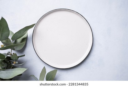An empty plate with eucalyptus branches on a light background. Festive table setting. Top view and place to copy. - Powered by Shutterstock