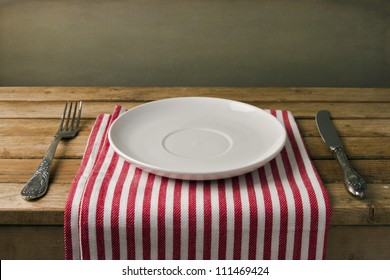 Empty plate with fork and knife on wooden table. Table arrangement.