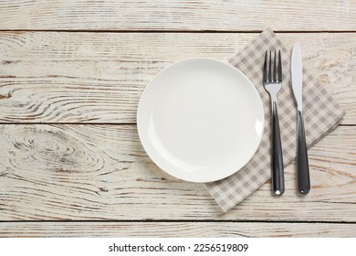 Empty plate, fork and knife on white wooden table, flat lay. Space for text - Shutterstock ID 2256519809