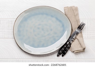 Empty plate with fork and knife on white wooden table. Flat lay with copy space