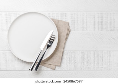 Empty plate, fork and knife on wooden table, overhead view with copy space - Powered by Shutterstock