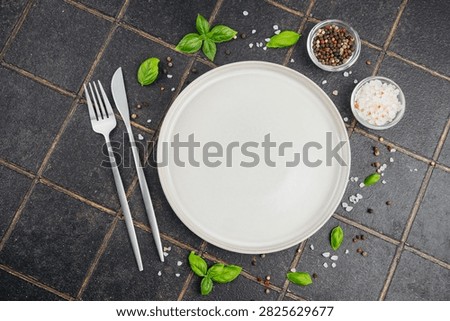 Empty plate with fork, knife, salt, pepper, and basil.
