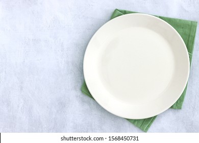 Empty Plate On Grey Stone Table And Napkin. Food Background For Menu, Recipe. Table Setting. Flatlay, Top View. Mockup For Restaurant Dish