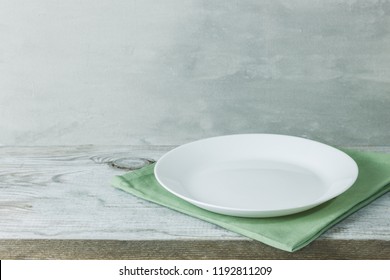 Empty plate on tablecloth on wooden table over grunge blue background