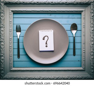 Empty Plate With A Question Mark Drawn On A Notepad On A Blue Table, Food Concept