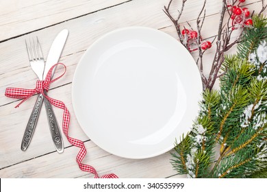 Empty Plate, Silverware And Christmas Tree. View From Above Over White Wooden Table Background