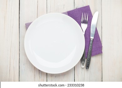 Empty Plate And Silverware Over White Wooden Table Background. View From Above