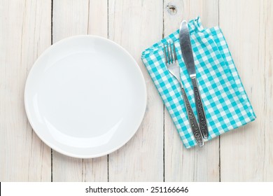 Empty Plate, Silverware And Towel Over Wooden Table Background. View From Above With Copy Space 