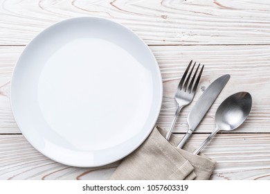 empty plate spoon fork and knife on table - Shutterstock ID 1057603319