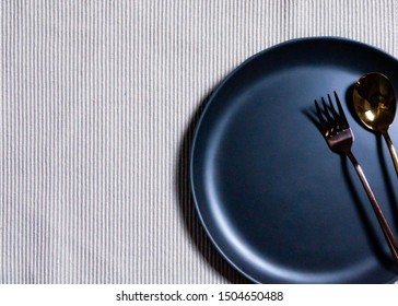 Empty plate with spoon and fork on Napery background, table setting 