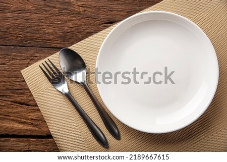 empty plate spoon fork on table. Table setting on wooden table background