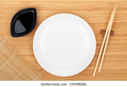 Empty Plate, Sushi Chopsticks And Soy Sauce On Bamboo Table