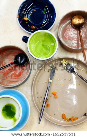 empty plates and cups after eating, waste food after raw healthy breakfast on the table. vertical photo