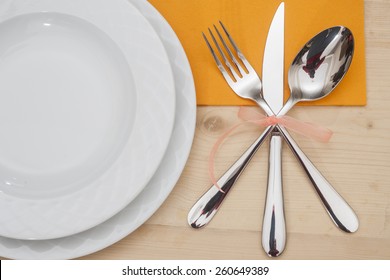  Empty plates with fork, spoon and knife on a wooden table