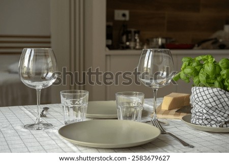 empty plates on the table, spring cozy home table setting with glasses and fresh basil on light tablecloth. Top view, copy space. background for menu