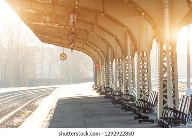 Empty platform with clock at railway station, sunny day