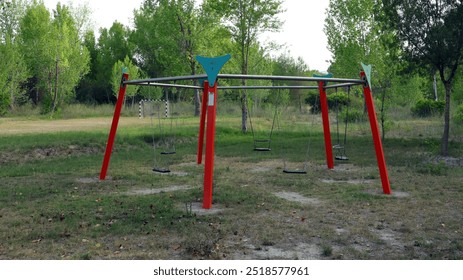 An empty playground features a large swing set with multiple swings, set in a peaceful park. Lush green trees surround the area, creating a calm atmosphere.