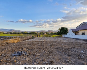 An empty plot of land, ready for construction, surrounded by lush green rice fields, offering a peaceful rural setting