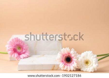 Empty podium boxes for presentation of cosmetic products. Marble boxes and pastel flowers  beige background
