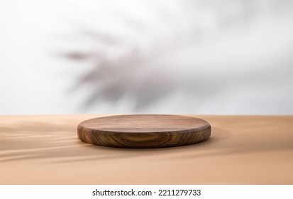 Empty podium with a shadow palm leaf. A round wooden stage on a beige table. Minimal abstract background for product presentation. Copy space.