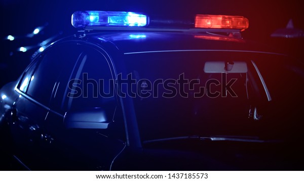 Empty police car with flashing lights standing on\
road, officers driving to\
call