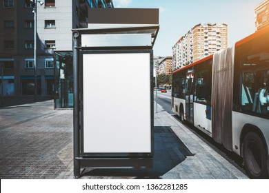 An Empty Poster Mock-up On An Outer Side Of The Bus Stop; Advertising Billboard Placeholder Template On The Stop Of Public Transport With A Bus On The Right; A Mockup Of A Blank White Outdoor Banner