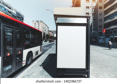 An Empty Poster Mock-up On An Outer Side Of The Bus Stop; Advertising Billboard Placeholder Template On The Stop Of Public Transport With A Departing Bus On The Left; A Mockup Of A Blank White Banner