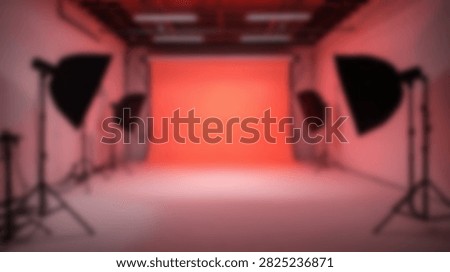 An empty professional photography studio set up with a vibrant red backdrop and professional lighting equipment, ready for a photoshoot.