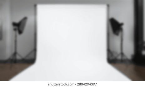 An empty professional photography studio setup featuring a seamless white backdrop and two studio lights on stands, ready for a photoshoot.