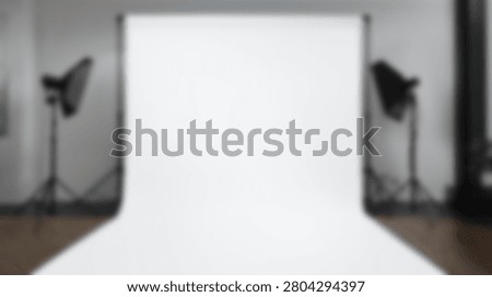An empty professional photography studio setup featuring a seamless white backdrop and two studio lights on stands, ready for a photoshoot.