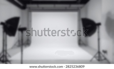 An empty professional photography studio setup featuring two softbox lights and a seamless white backdrop, ready for a photoshoot.