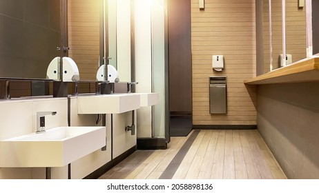 Empty Public Bathroom With White Sinks And Wide Wall Mirror