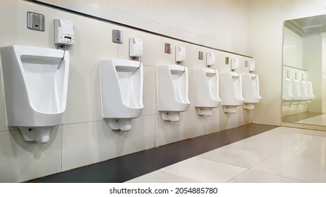 Empty Public Bathroom And Wide Wall Mirror, Selective Focus On Left Urinal