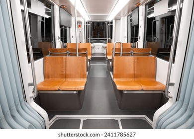 Empty public transportation tram car. Inside shot, nighttime, no people, empty seats.