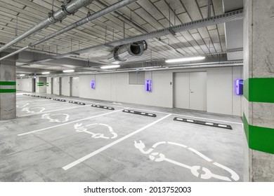 Empty public underground parking lot or garage interior with concrete stripe painted columns and signs. Electric car charging place. - Shutterstock ID 2013752003