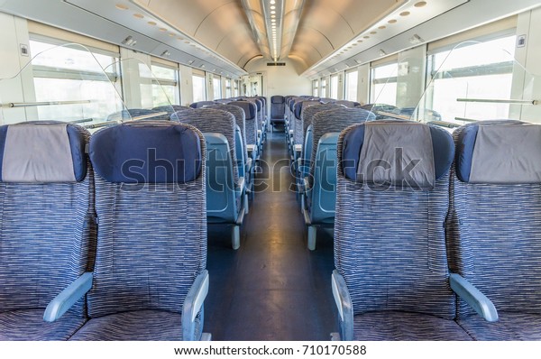 Empty rail passenger carriage seat rows with\
dimishing perspective